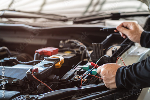 Professional mechanic man holding multimeter tool for testing and troubleshooting failure of a car