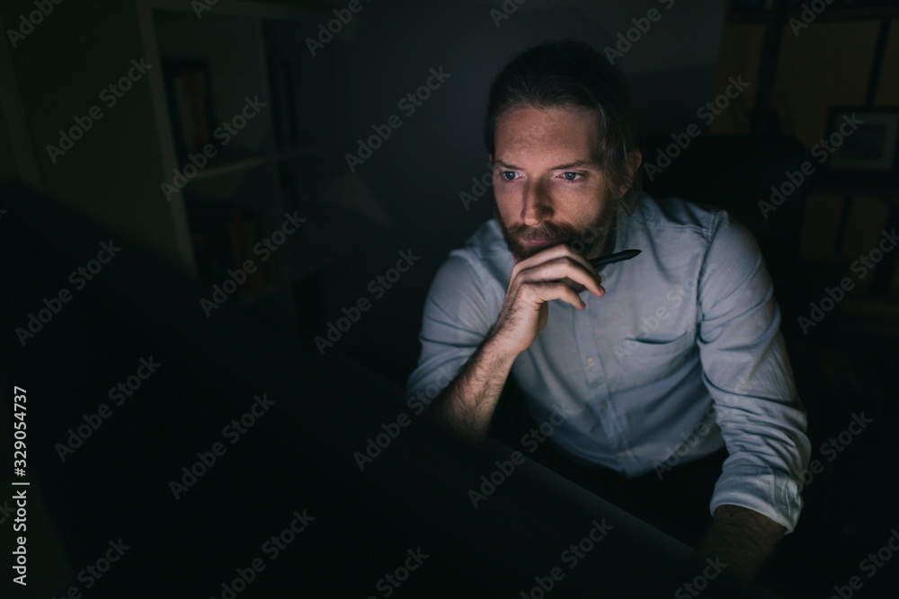 Bearded man working on computer from his home office Bearded man working on computer from his home office