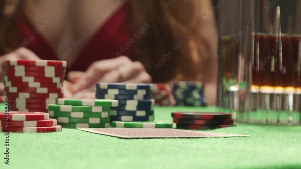 Poker player checking his hand, holding Queen and King combination chips cards Poker player checking his hand, holding Queen and King combination chips cards