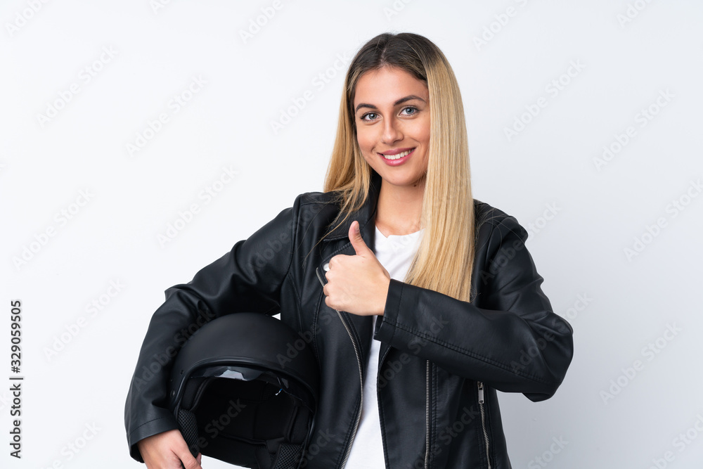 Young Uruguayan woman with a motorcycle helmet over isolated white background giving a thumbs up gesture Young Uruguayan woman with a motorcycle helmet over isolated white background giving a thumbs up gesture