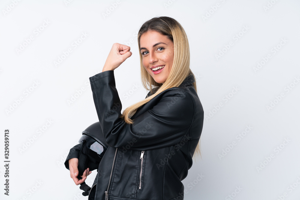 Young Uruguayan woman with a motorcycle helmet over isolated white background making strong gesture Young Uruguayan woman with a motorcycle helmet over isolated white background making strong gesture