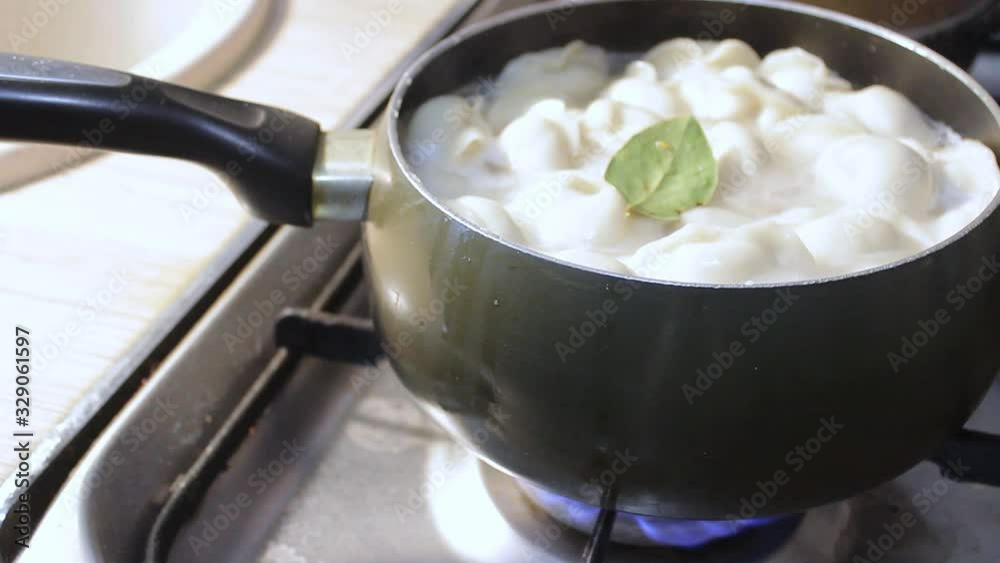 meat dumplings are cooked in boiling water in the kitchen. the chef is stirring the broth with a cooking device meat dumplings are cooked in boiling water in the kitchen. the chef is stirring the broth with a cooking device