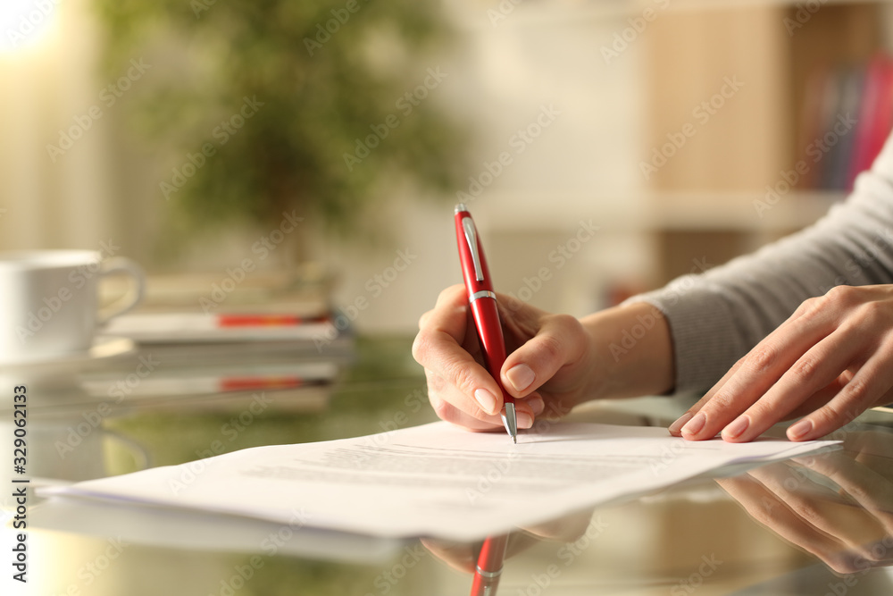 Woman signing document with pen on a desk at home - obrazy, fototapety, plakaty 