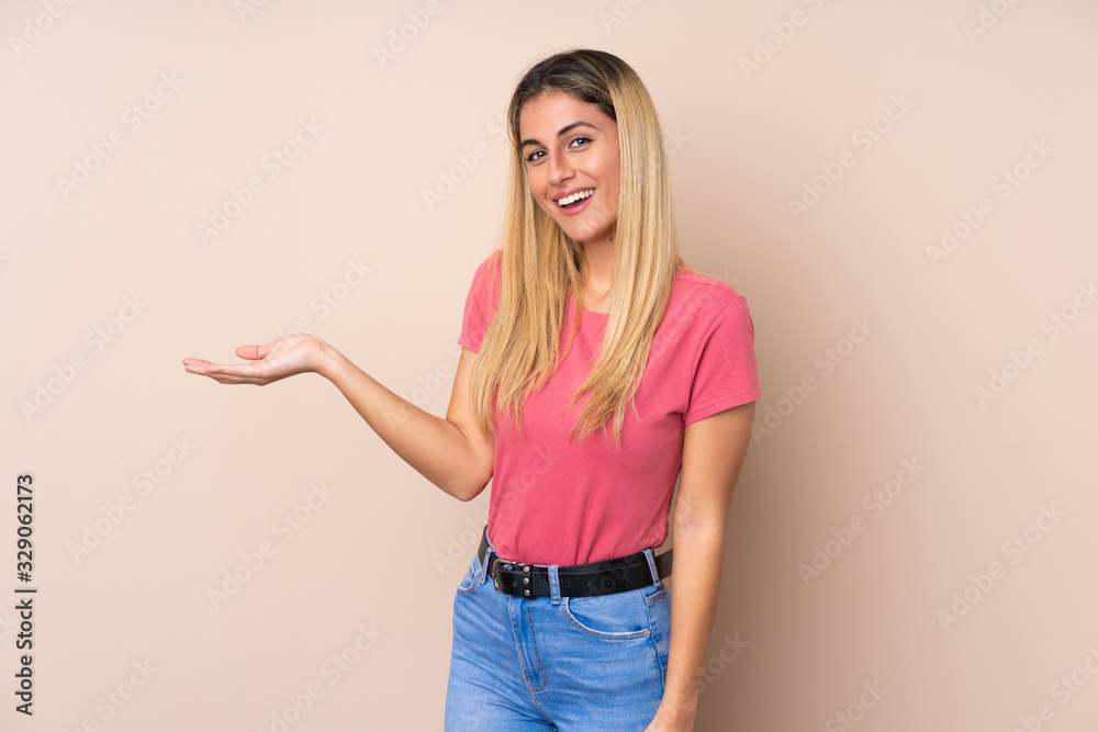 Young Uruguayan woman over isolated background holding copyspace imaginary on the palm to insert an ad Young Uruguayan woman over isolated background holding copyspace imaginary on the palm to insert an ad
