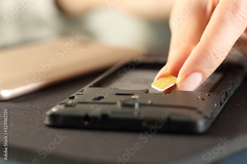 Fotografi Woman inserting sim card on smart phone on a desk