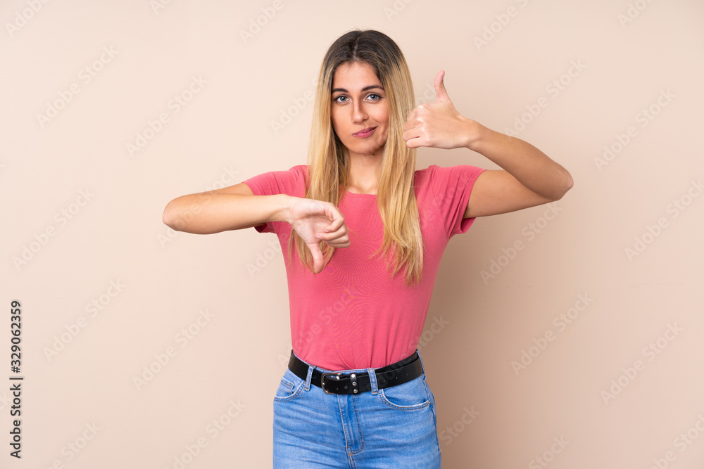 Young Uruguayan woman over isolated background making good-bad sign. Undecided between yes or not Young Uruguayan woman over isolated background making good-bad sign. Undecided between yes or not