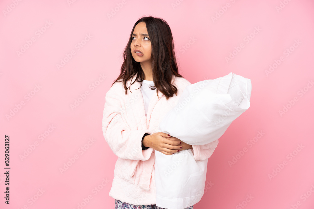 Young woman in pajamas isolated on pink background with confuse face expression Young woman in pajamas isolated on pink background with confuse face expression