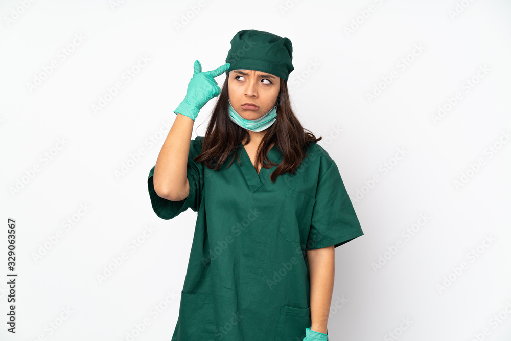 Surgeon woman in green uniform isolated on white background making the gesture of madness putting finger on the head Surgeon woman in green uniform isolated on white background making the gesture of madness putting finger on the head