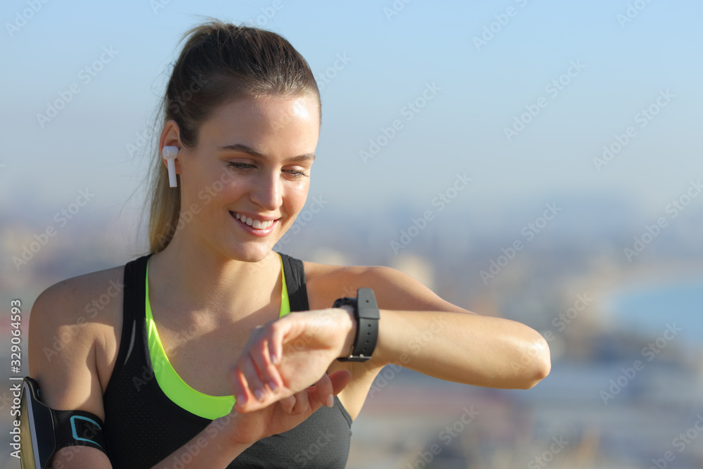 Happy runner with earbuds checking smart watch Happy runner with earbuds checking smart watch