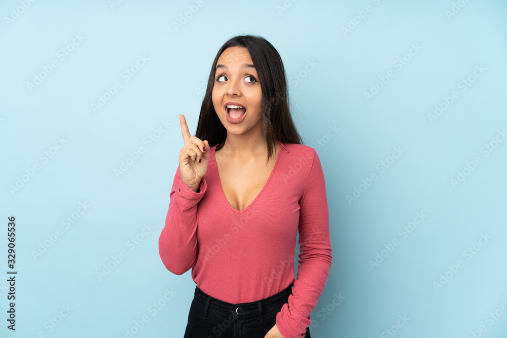Young mixed race woman isolated on blue background intending to realizes the solution while lifting a finger up Young mixed race woman isolated on blue background intending to realizes the solution while lifting a finger up