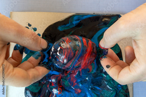 Woman's hands are painting eggs for easter with glowing colours. Decorating eggs with trendy blue colours and abstract paints photo