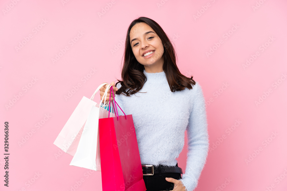 Young woman with shopping bag over isolated pink background laughing
