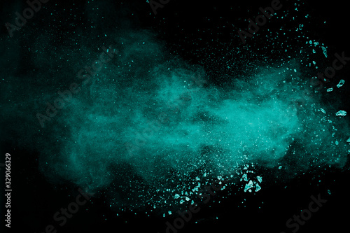 Abstract splash of green colored powder on black background.Green powder explosion.