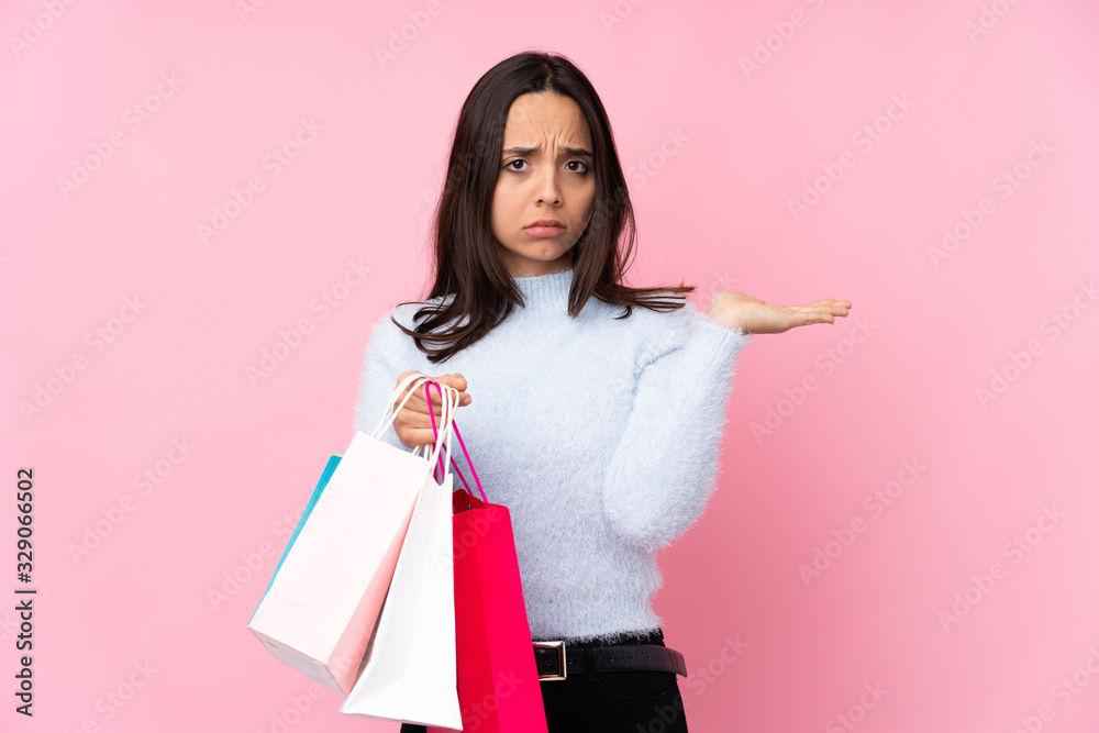 Young woman with shopping bag over isolated pink background unhappy for not understand something Young woman with shopping bag over isolated pink background unhappy for not understand something