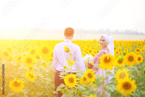 Smiling young islamic couple portrait on sunflowers field photo