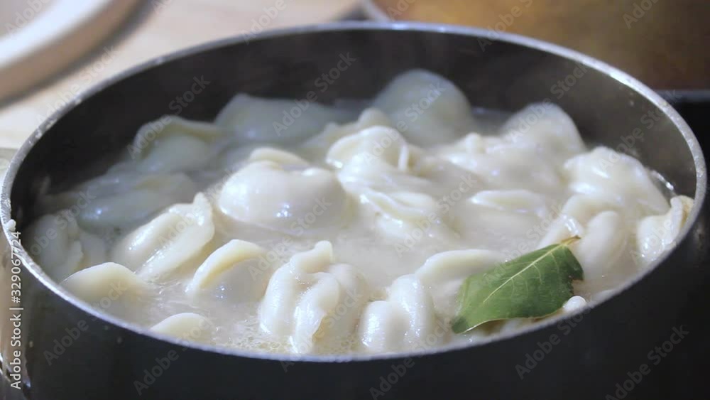 meat dumplings are cooked in boiling water in the kitchen. the chef is stirring the broth with a cooking device meat dumplings are cooked in boiling water in the kitchen. the chef is stirring the broth with a cooking device