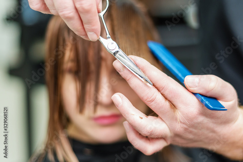 Hairdresser cutting hair of woman.