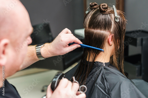 Hairdresser combs hair of woman.