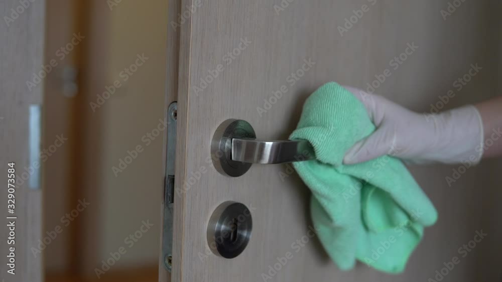 Woman with rubber gloves clean office doors handle, spray disinfectant, corona virus protection.