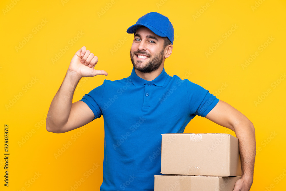 Delivery man over isolated yellow background proud and self-satisfied Delivery man over isolated yellow background proud and self-satisfied