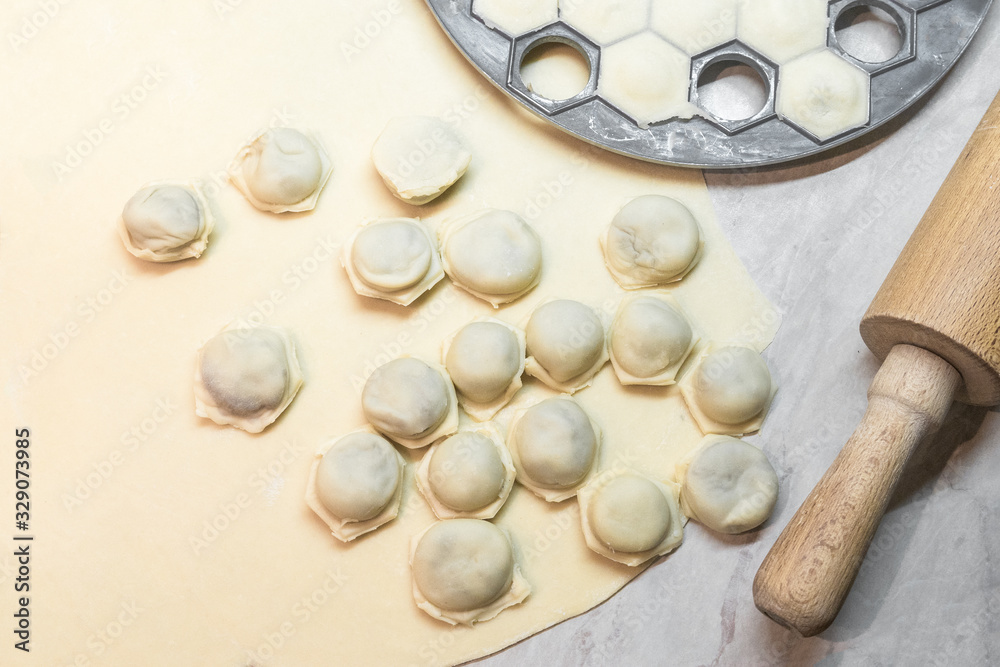 Raw homemade dumplings with meat on rolled dough close up. Tools for cooking ravioli. National traditional food Raw homemade dumplings with meat on rolled dough close up. Tools for cooking ravioli. National traditional food