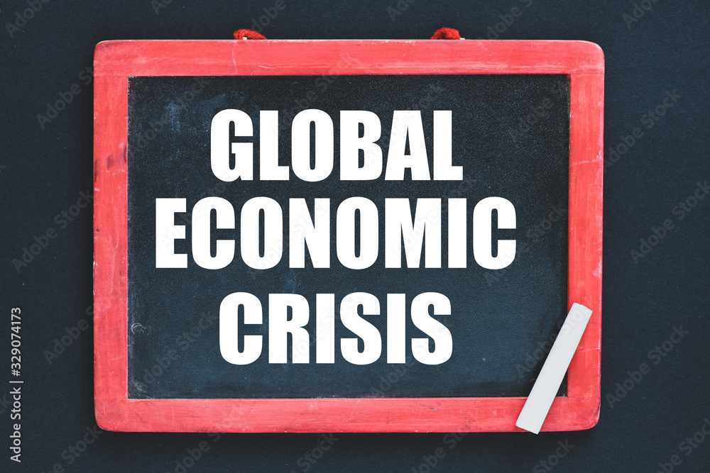 The global economic crisis written on a chalk board and a black background. Business concept. The global economic crisis written on a chalk board and a black background. Business concept.