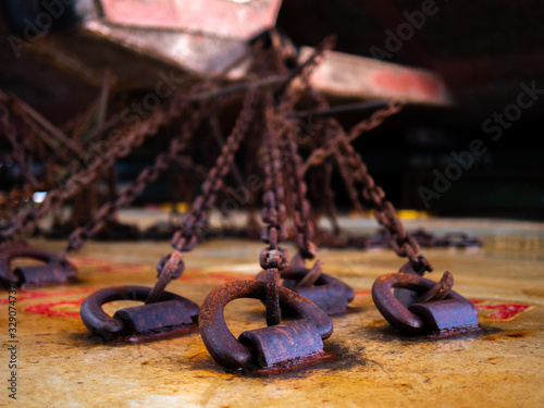 Fototapeta Close up of the rusty lashing chains attached to rusty d-rings on deck securing heavy lift cargo on the cargo vessel