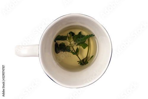 Fresh herbal tea made from green Melissa leaves in ceramic mug isolated on white. Healing, homeopathic drink. alternative medicine