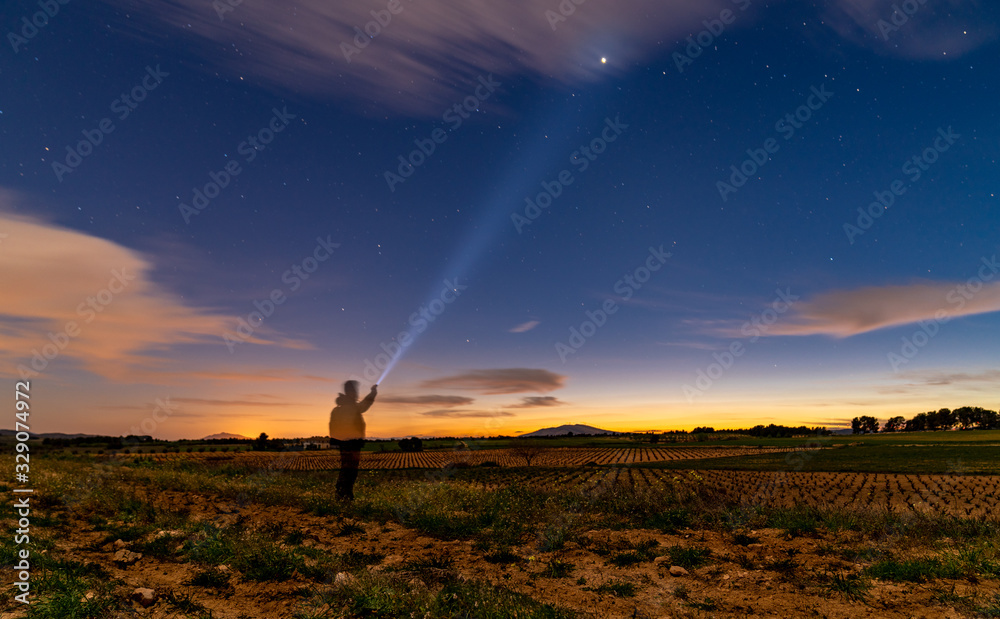 silhouette of man in night landscape lighting a star