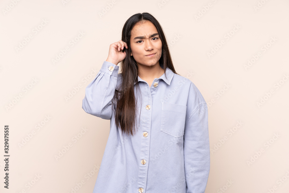 Young Indian woman isolated on beige background having doubts Young Indian woman isolated on beige background having doubts