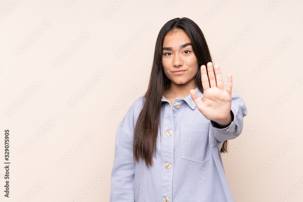 Young Indian woman isolated on beige background making stop gesture Young Indian woman isolated on beige background making stop gesture