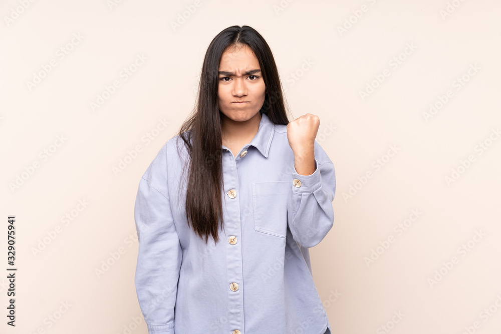 Young Indian woman isolated on beige background with unhappy expression Young Indian woman isolated on beige background with unhappy expression