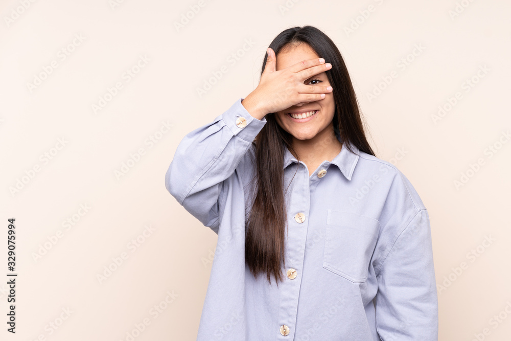 Young Indian woman isolated on beige background covering eyes by hands and smiling Young Indian woman isolated on beige background covering eyes by hands and smiling