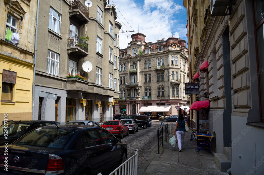 Naklejka premium Starożytna europejska wąska uliczka z brukiem. Stare, otynkowane kolorowe elewacje domów. Romantyczne, przytulne uliczki. Średniowieczna Europa. Lwów, Ukraina, 18 lipca 2017 r