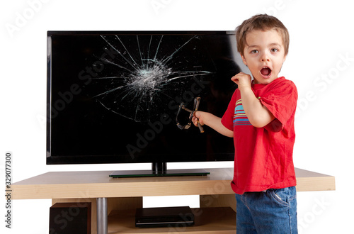 Tableau sur toile Shocked little boy holding a slingshot standing in front of a TV with broken screen