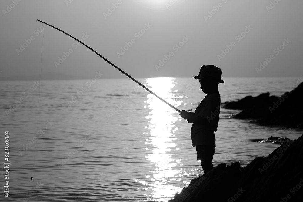 Silhouette of a boy with a fishing rod