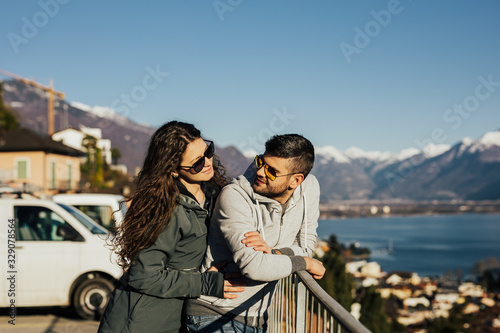Travelers couple look at each other near snowy mountain and lake. Travel and active life concept together. Adventure and travel in the mountains region in the Switzerland. 