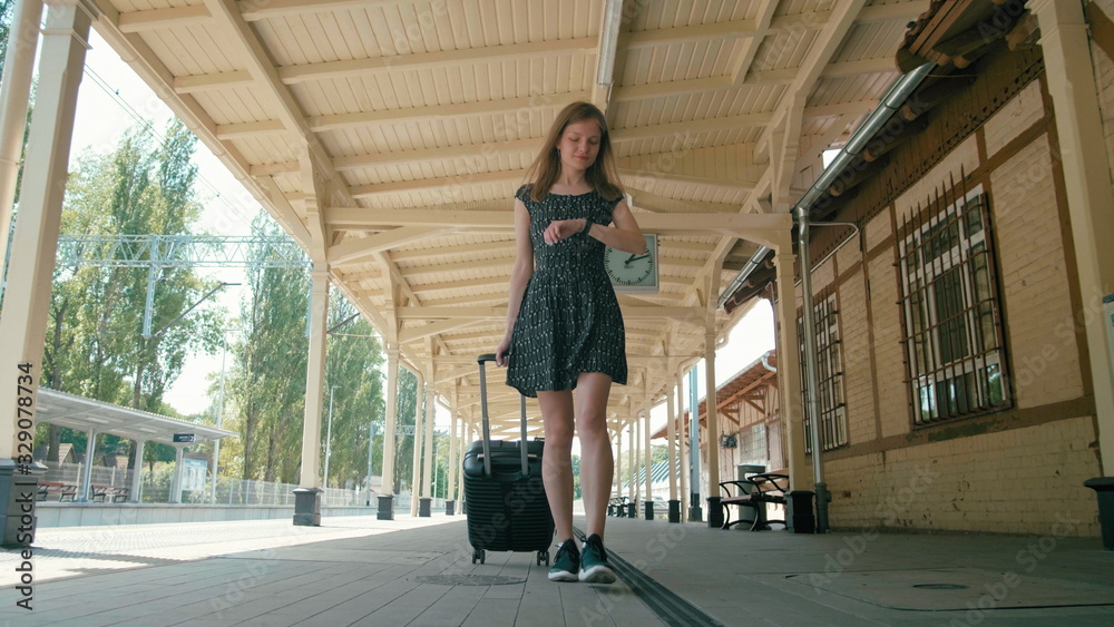 Young Slender Woman is Traveling and Walking on Vintage Train Station with Suitcase