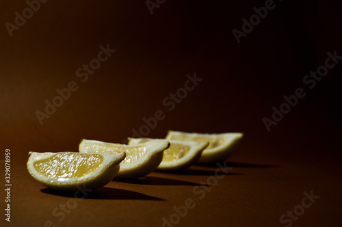 four slices of yellow lemon on a brown background horizontal orientation photo