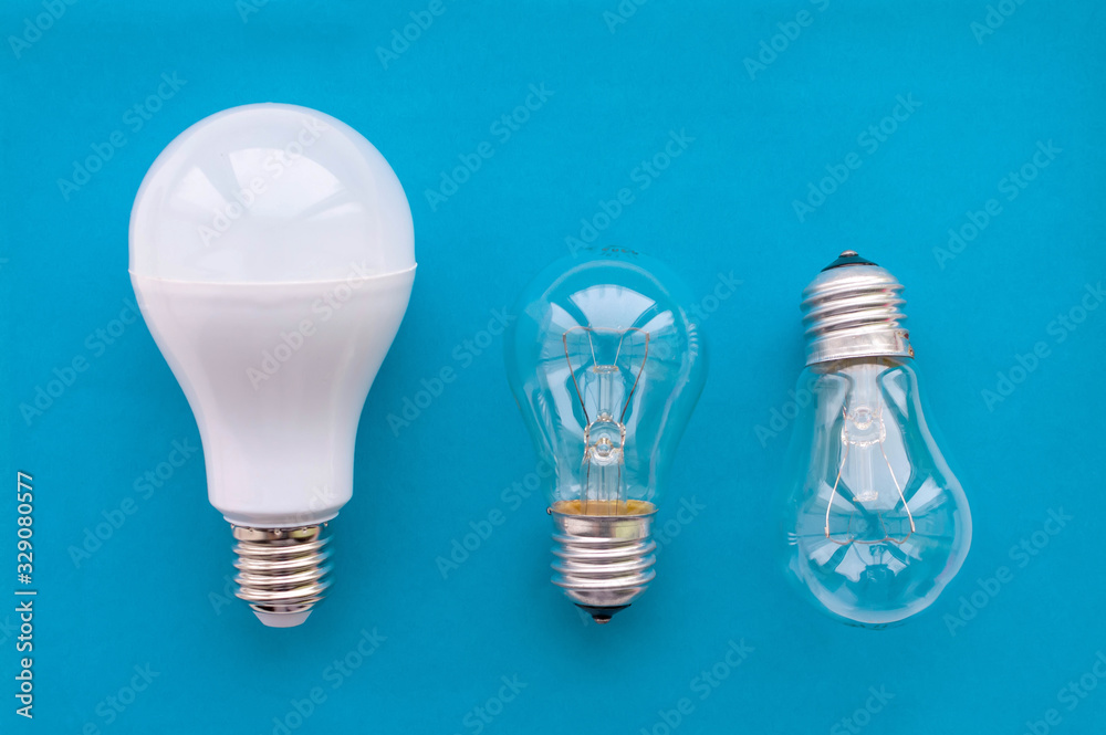 Energy-saving lamp with incandescent lamps in a row on a blue background. The concept of saving energy. Energy-saving lamp with incandescent lamps in a row on a blue background. The concept of saving energy.