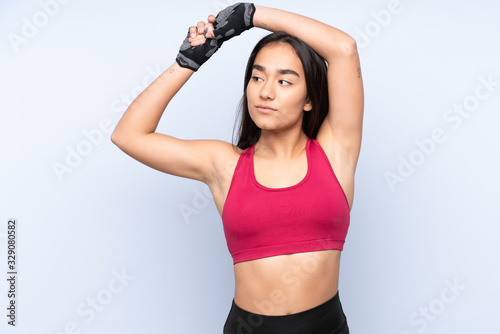 Young Indian sport woman isolated on blue background stretching