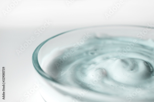 Facial scrub texture in glass container with selective focus, close-up. Cosmetic body and hair care product on white background