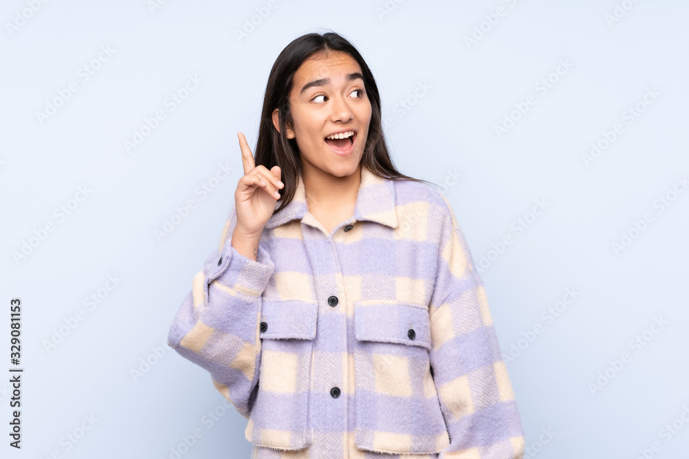 Young Indian woman isolated on blue background intending to realizes the solution while lifting a finger up Young Indian woman isolated on blue background intending to realizes the solution while lifting a finger up