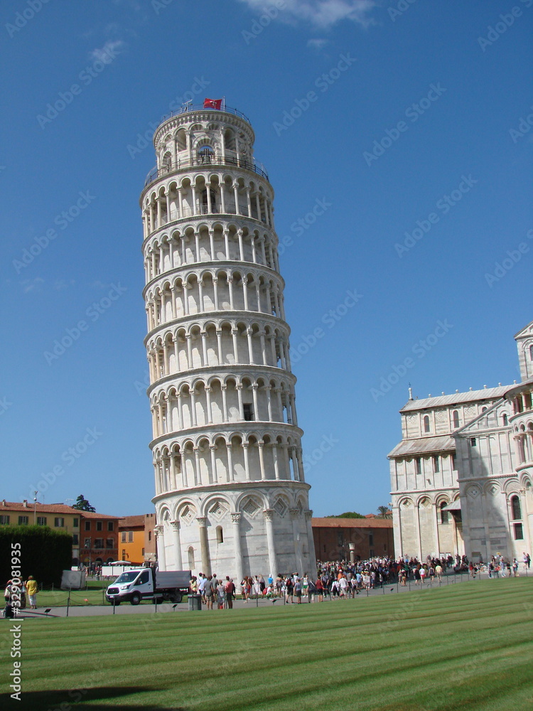 Panorama of a falling ancient tower surrounded by numerous tourists from all over the world.