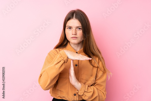 Ukrainian teenager girl over isolated pink background making time out gesture © luismolinero
