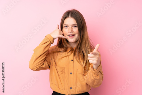 Ukrainian teenager girl over isolated pink background making phone gesture and pointing front