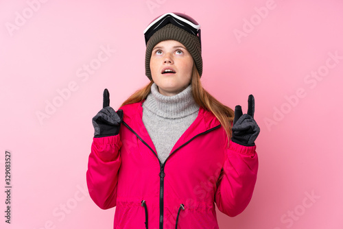 Ukrainian teenager skier girl with snowboarding glasses over isolated pink background pointing with the index finger a great idea