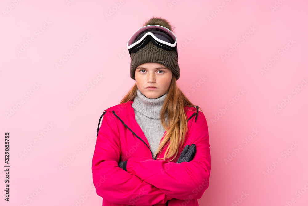 Ukrainian teenager skier girl with snowboarding glasses over isolated pink background keeping arms crossed