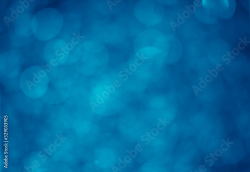 Blue glitter vintage lights background. White bokeh on blue background.