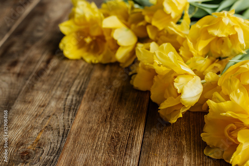 Large bouquet of yellow tulips on a wooden table